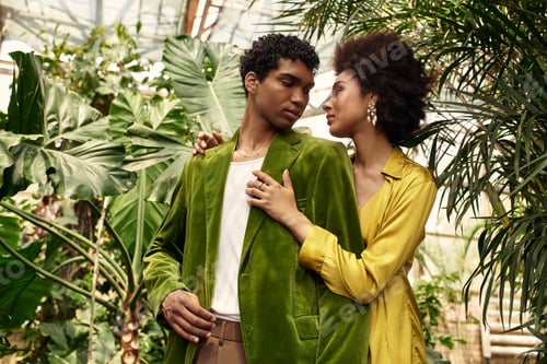 Preview: Young couple embraces in a lush greenhouse filled with vibrant greenery and warmth of love