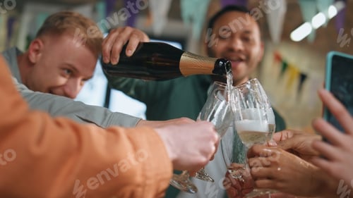 Preview: Smiling friends pouring wine in glasses at birthday party close up. Team success