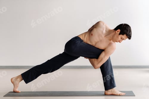 Preview: A man with a bare torso trains standing up, doing stretching in the gym