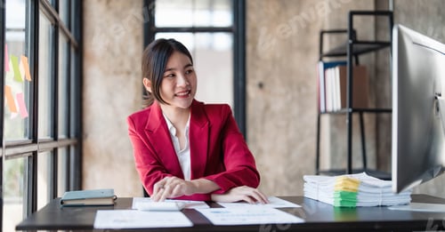 Preview: Portrait of smiling Asian businesswoman enjoying her work on her laptop at the office.