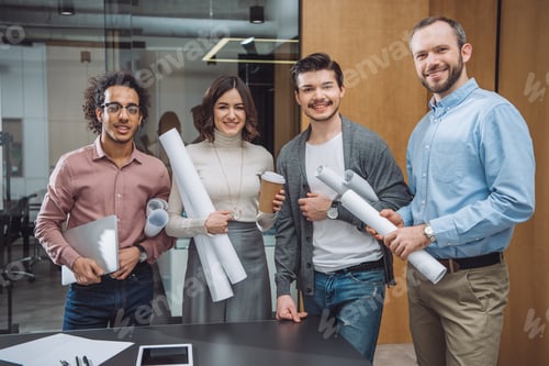 Preview: group of successful architects with rolled plans at office