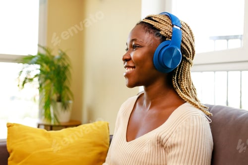 Preview: latin hispanic woman listen music while sitting on sofa in living room