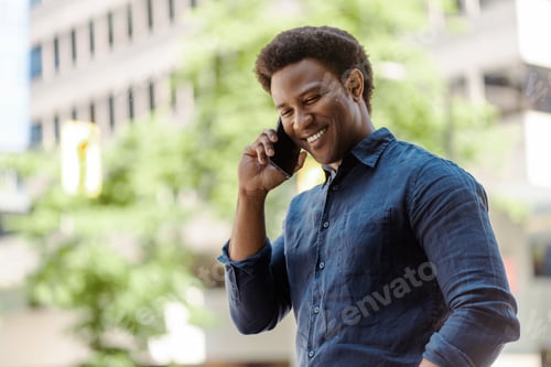 Preview: Young businessman having a pleasant conversation on his phone in the city