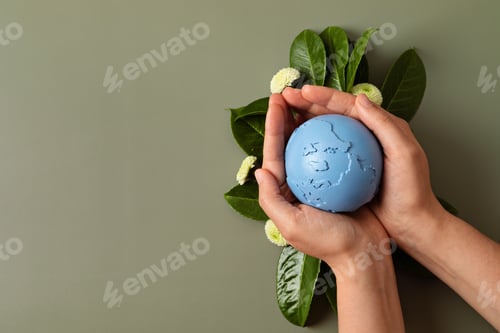 Preview: Hands Holding a Blue Globe Surrounded by Greenery