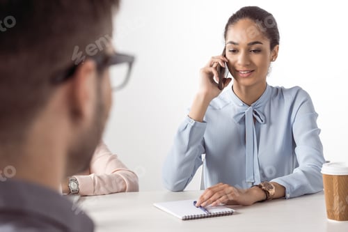 Preview: young businesswoman talking on smartphone while man waiting at meeting