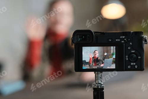 Preview: Young Woman Recording Video on Camera Indoors