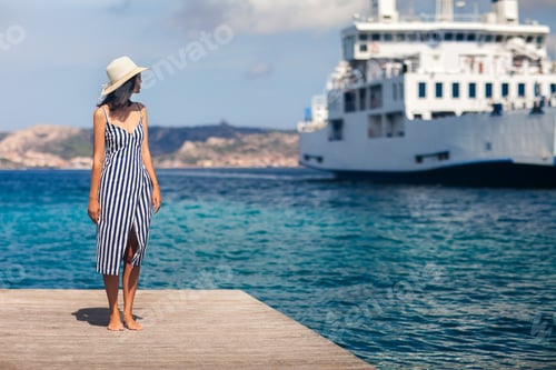 Preview: Beautiful young woman in hat relax on wooden pier on Sardinia beach