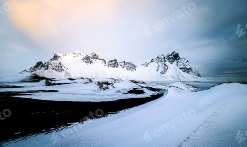 Preview: Scenic view of the Vestrahorn Mountains covered with snow under dusk sky in south-east Iceland