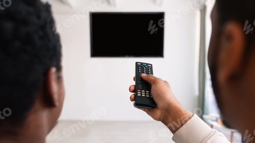 Preview: Black couple watching TV and using remote controller