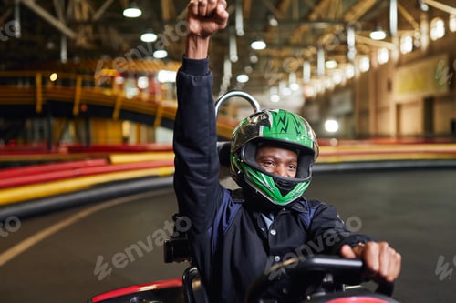 Preview: Go kart speed drive indoor race, excited african american driver in helmet celebrating victory