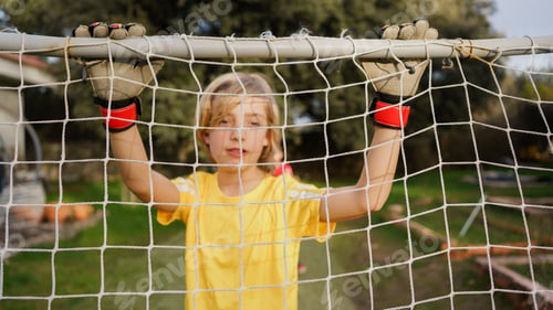 Preview: Young boy goalkeeper holding soccer goal net
