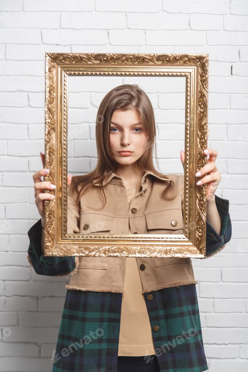 Preview: Young woman holds the frame in front of her. Boundary and stereotype concept