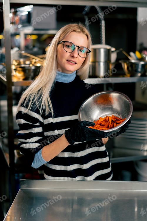 Preview: girl with glasses in kitchen stands with a bowl of sweet potato demonstrating looking at the camera