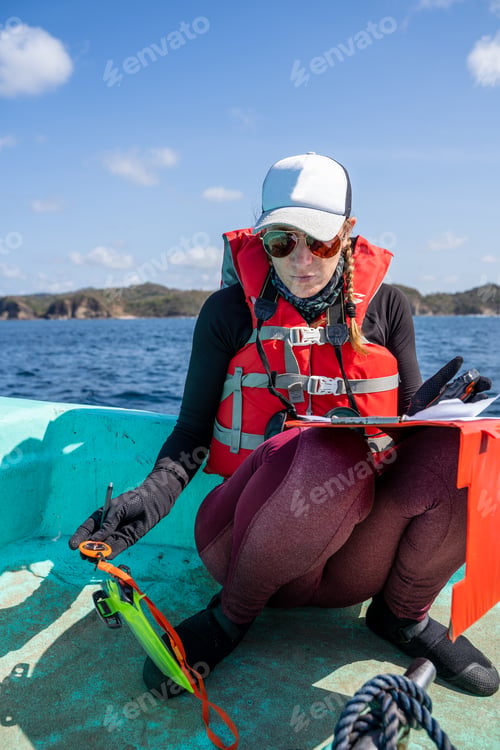 Preview: Equipped marine biologist writing notes on a paper while working