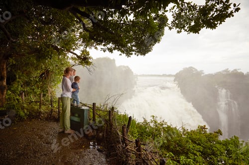 Preview: Travelers mesmerized by the majestic waterfall view amid lush nature