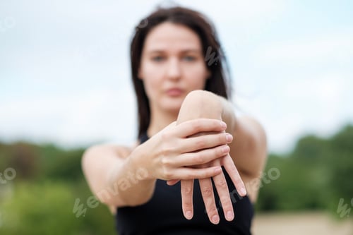 Preview: Portrait of yoga woman stretching her arms in a park in London.