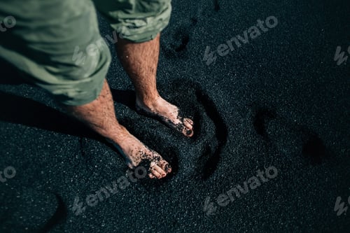 Preview: Man barefoot on black sand beach in iceland