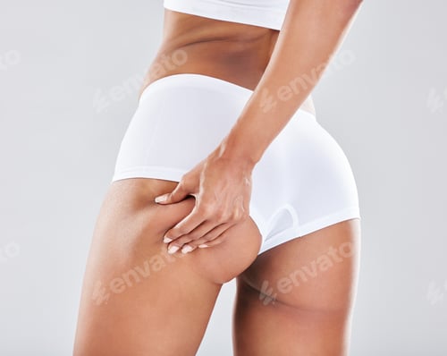 Preview: Cellulite, stretch marks and woman touching her butt for insecurity isolated on grey studio backgro