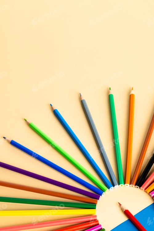Preview: Close up of multi coloured pencils in circle and copy space on blue and yellow background