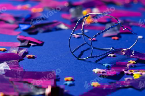 Preview: Glitter confetti lying on paper background close up