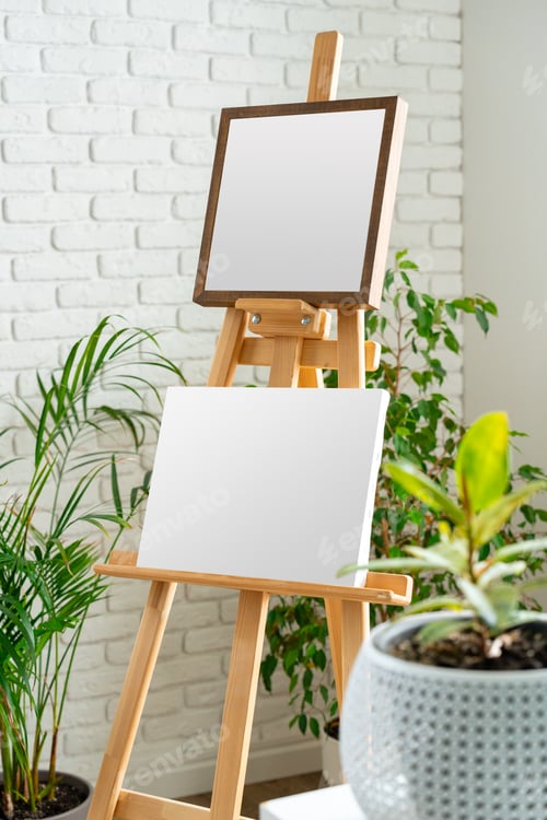 Preview: Empty easels stand ready for artistic creation in a bright indoor space surrounded by greenery