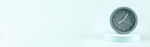 Preview: Green alarm clock on turquoise podium on monochrome background, web banner