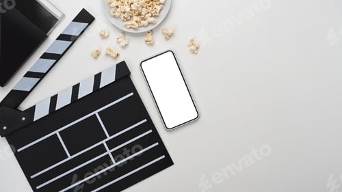 Preview: Above view of smart phone, clapboard and popcorn on white background.