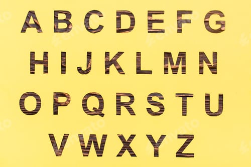 Preview: The letters of the English alphabet are cut out of yellow cardboard, a wooden background
