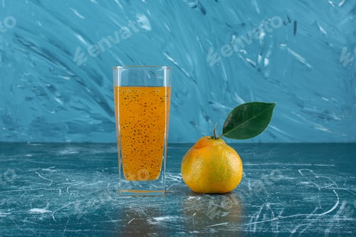 Preview: a glass of processed juice and tangerine on the blue background