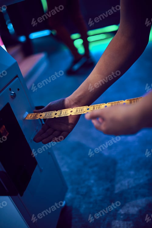 Preview: Close-up of teenage boy taking tickets from machine in an amusement arcade