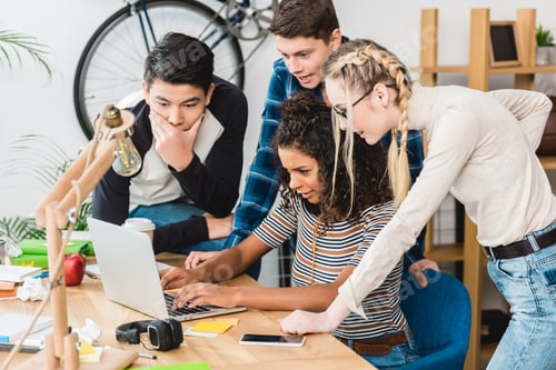 Preview: group of multiethnic teenagers looking at laptop at home