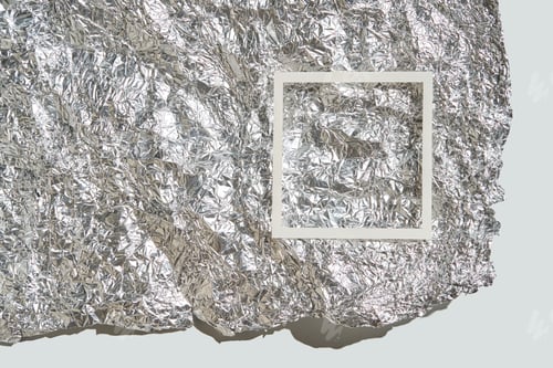 Preview: Crumpled silver foil background with white frame overlay on a light surface