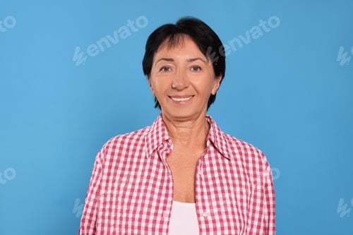 Preview: Portrait of smiling senior woman on light blue background