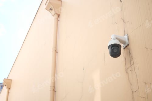 Preview: Security camera mounted on a cracked wall in a urban area