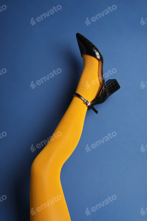 Preview: Woman wearing bright tights and high heel shoe on blue background, closeup