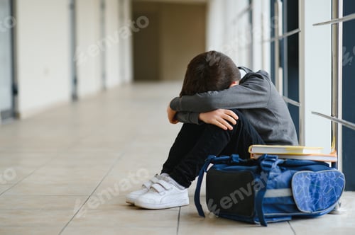 Preview: Upset boy sitting at school and crying after bullying by pupils classmates. child covered his face