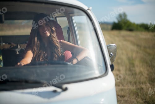 Preview: Smiling woman enjoying a road trip in a vintage car.