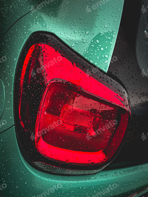 Preview: Close-up shot of the back of a green car, featuring wet rear and back lights
