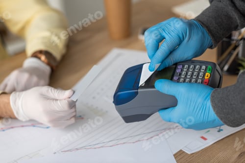 Preview: cropped view of delivery man holding payment terminal and credit card near businessman