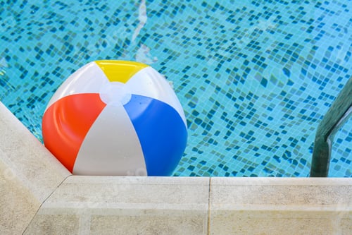 Preview: Inflatable beach ball floating in swimming pool, space for text
