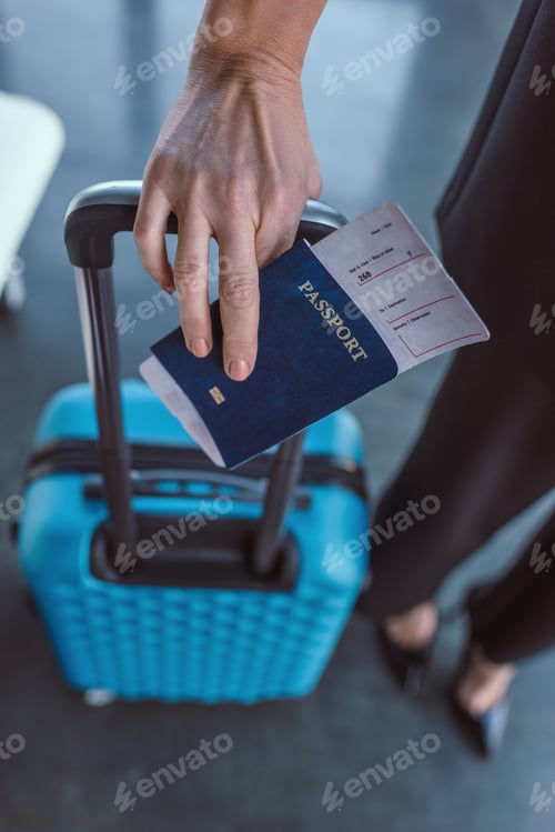 Preview: cropped shot of woman with suitcase and flight ticket in hand