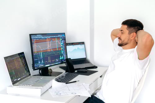 Preview: Stock trading, cryptocurrency concept. Male trader sitting at desk at home office monitoring stock