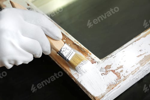 Preview: Repairman painting old window at table indoors, closeup
