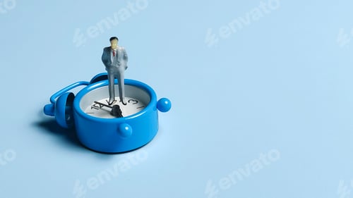 Preview: Businessman Figurine Standing on a Blue Alarm Clock