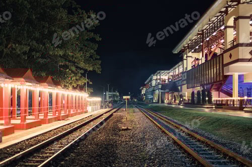Preview: Illuminated large building of train station with railway platform in the night