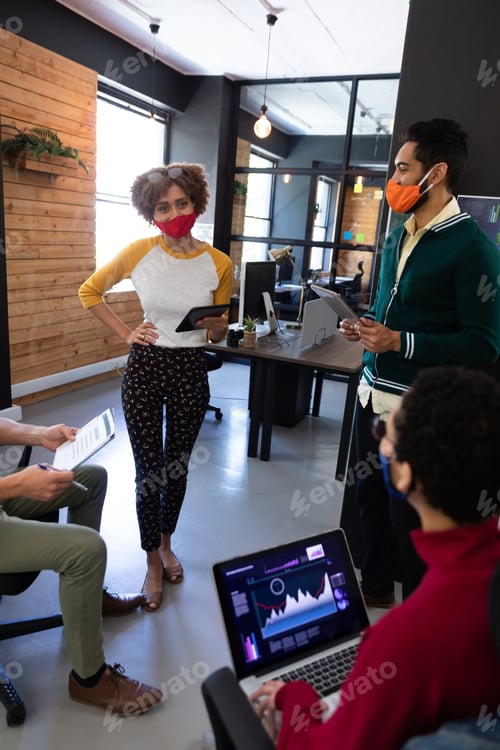 Preview: Diverse group of colleagues wearing masks having disussion in creative office