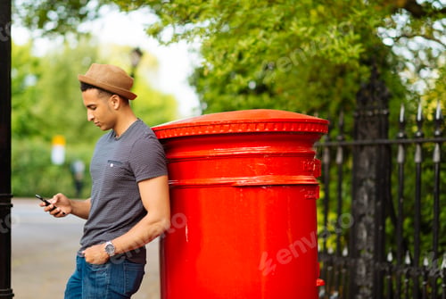Preview: Man leaning against mailbox using smartphone