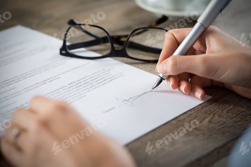 Preview: Woman Signing Document with Pen on Wooden Desk