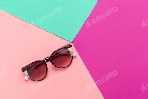 Preview: Sunglasses placed on colorful sheets of paper in bright shades during a sunny day