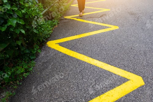Preview: Deviation but same direction. Woman is walking on a yellow zigzag line painted on asphaltic road